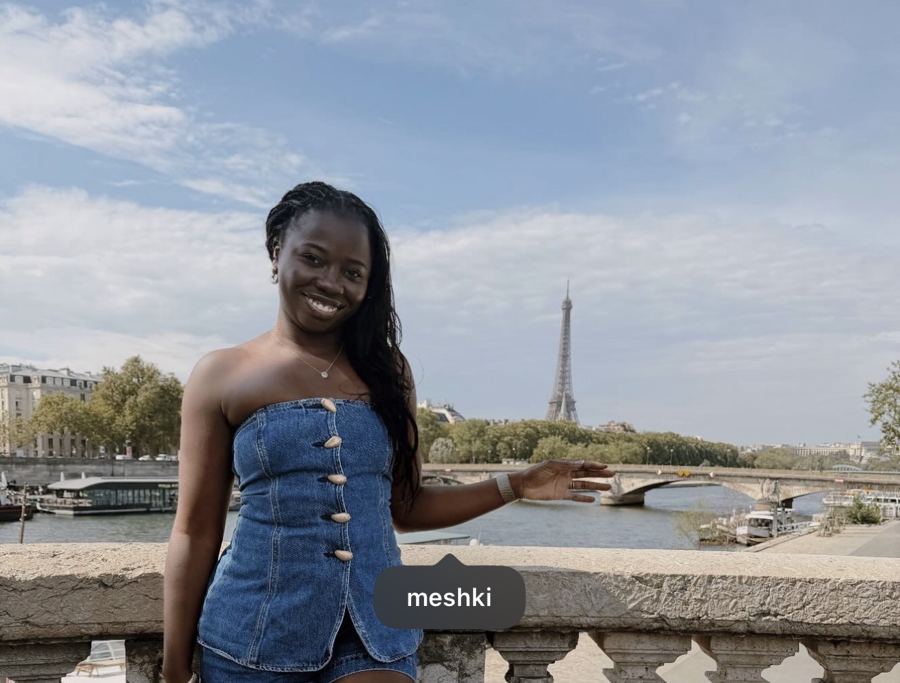 Maï on a bridge in Paris with the Eiffel Tower behind her